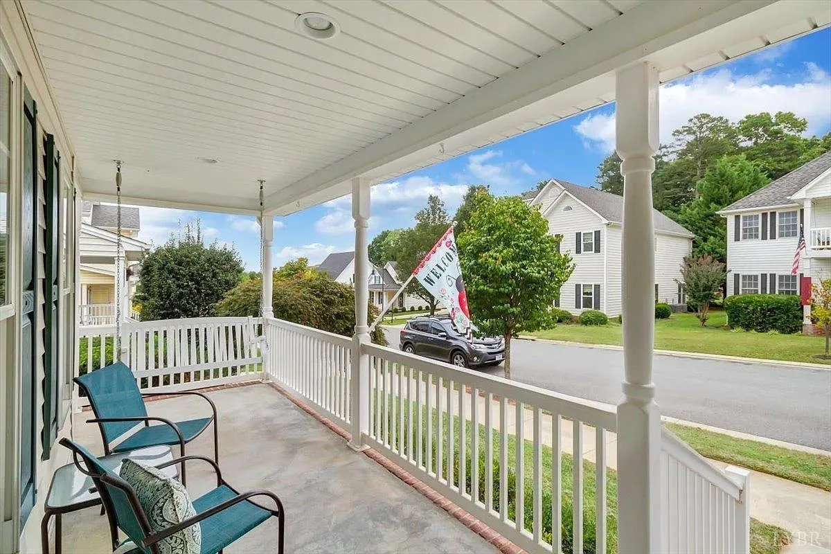 Covered front porch with white railings and chairs on a residential street