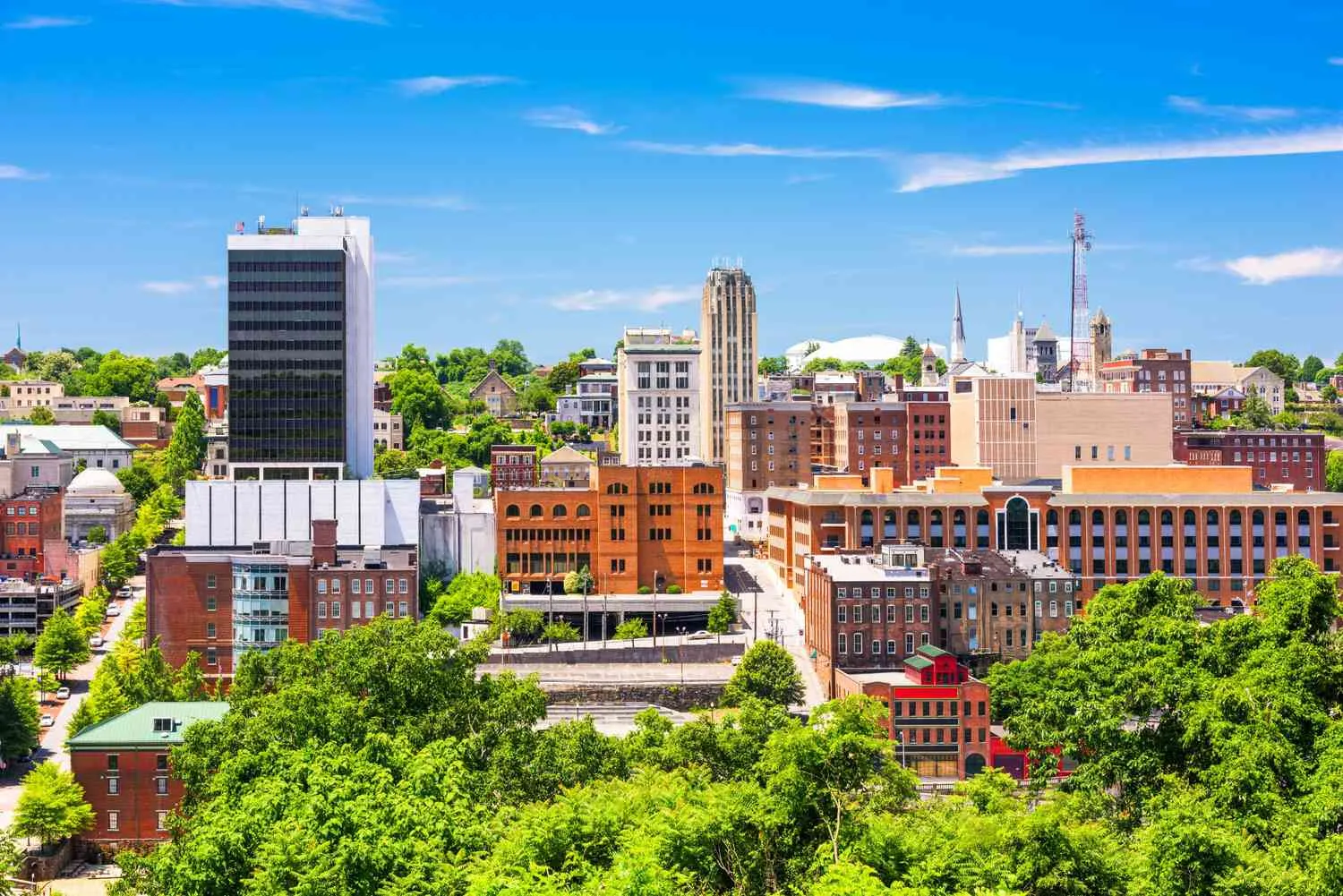 City skyline of brick buildings rising above green trees