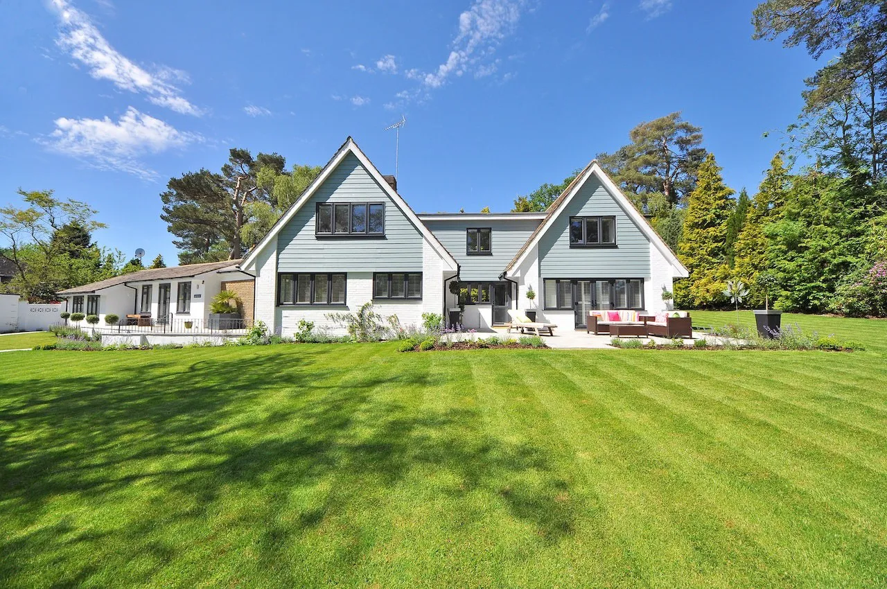 White farmhouse-style home with a dark roof and a wide green lawn