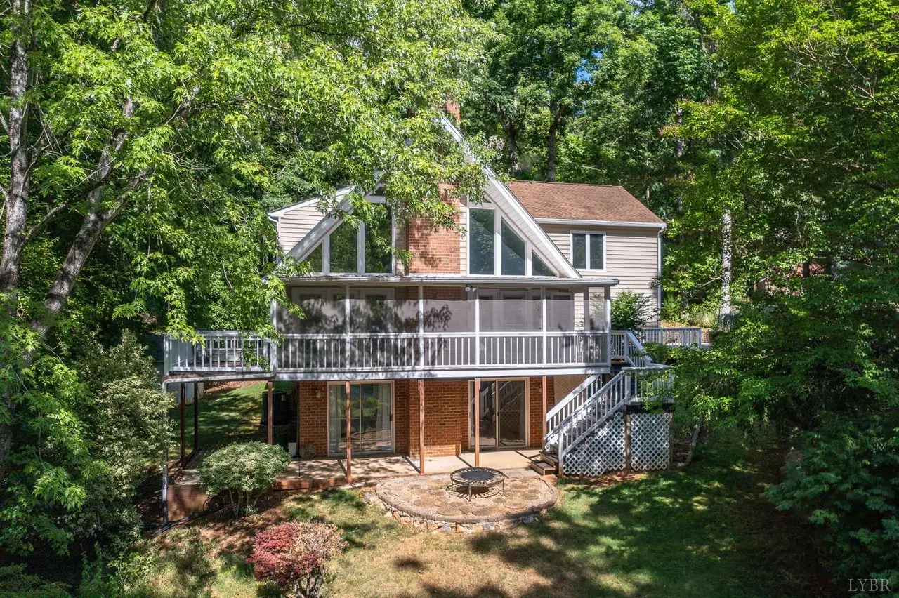 Back of the house with a deck and screened porch among trees at 107 Waterview Circle, Forest VA