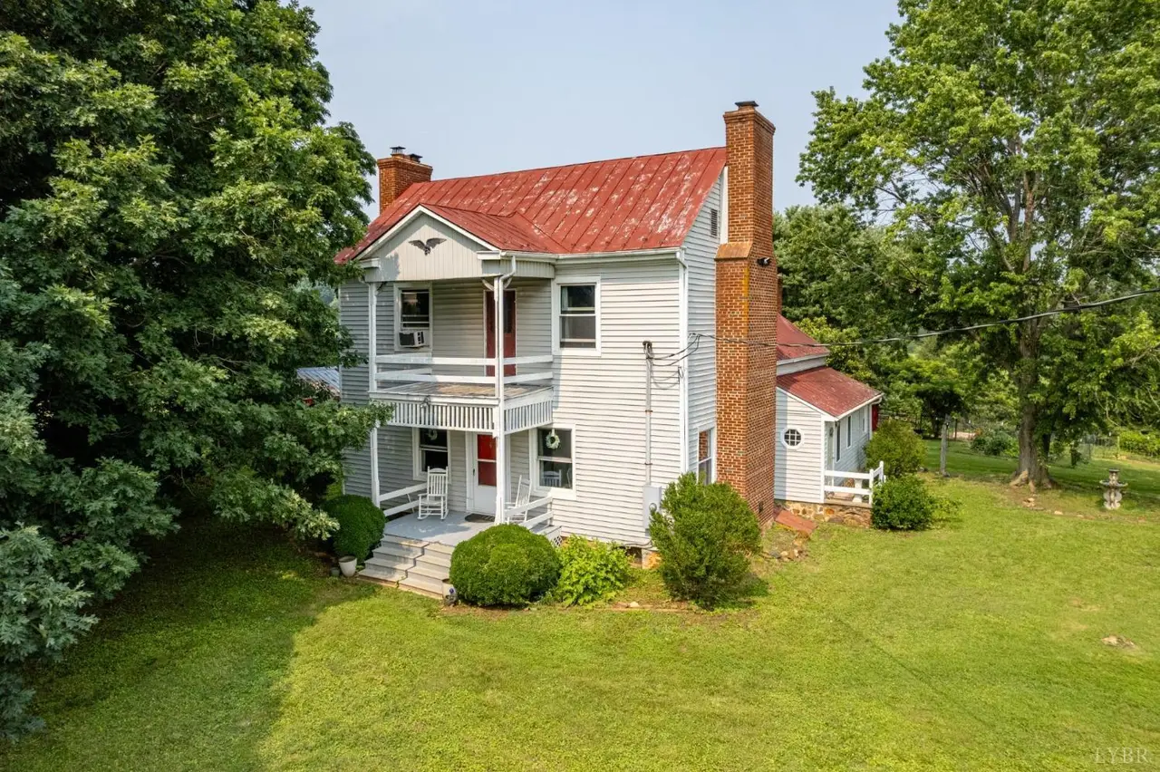 Front of the two-story house with a red metal roof and a two-level porch at 1086 Meadow Drive, Appomattox VA
