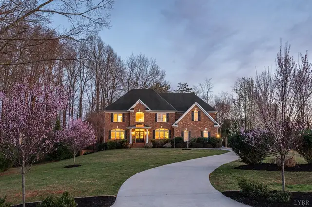Brick house with a curved driveway and flowering trees at dusk at 1108 Half Moon Court, Forest VA