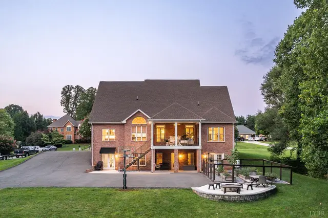 Back of the house with a lower patio and fire pit at dusk at 1118 Jefferson Dr W, Forest VA