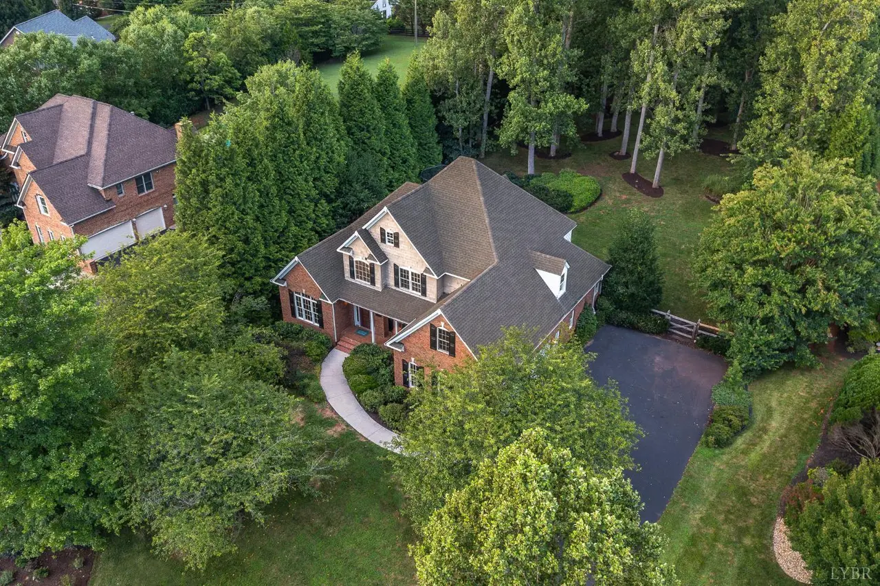 Aerial view of the brick two-story house with a curved walkway among trees at 1227 Jefferson Dr W, Forest VA
