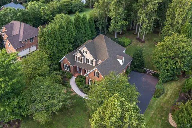 Aerial view of the brick two-story house with a curved walkway among trees at 1227 Jefferson Dr W, Forest VA