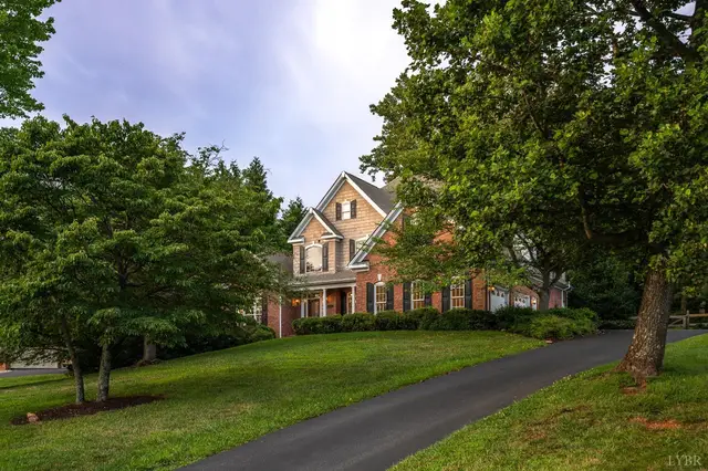 Front of the house, brick two-story behind trees with a long paved driveway at 1227 Jefferson Dr W, Forest VA