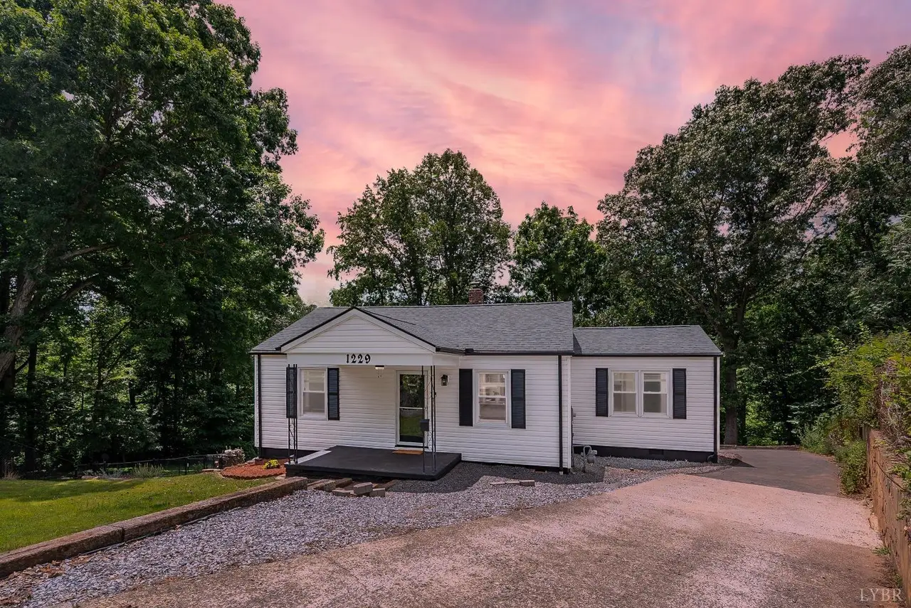 Front of the house, white one-story with black shutters and gravel drive at sunset at 1229 Stratford Road, Lynchburg VA