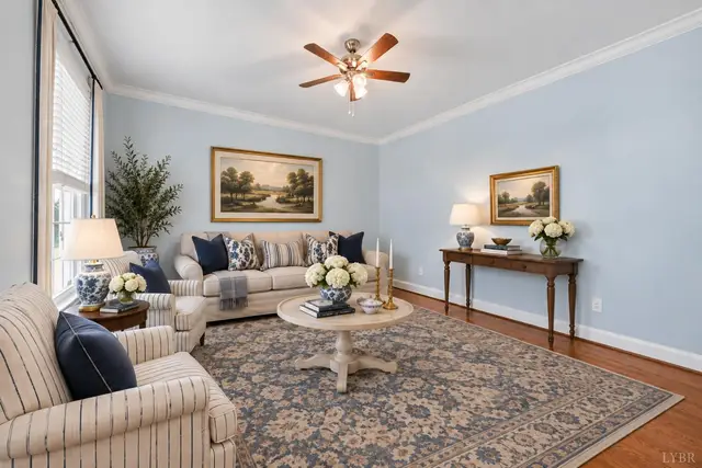 Sitting room with a striped armchair, round coffee table and landscape paintings at 1351 Country Estates Drive, Lowry VA