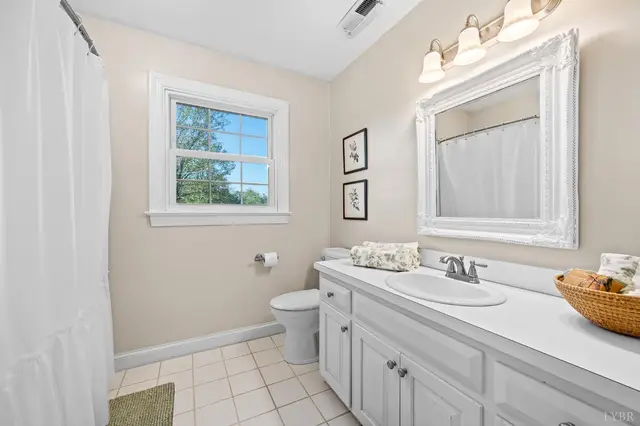 Bathroom with a white vanity, framed mirror and tile floor at 1351 Country Estates Drive, Lowry VA