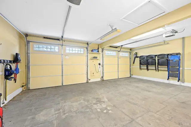 Two-car garage with yellow walls and folding chairs hung on the wall at 1351 Country Estates Drive, Lowry VA