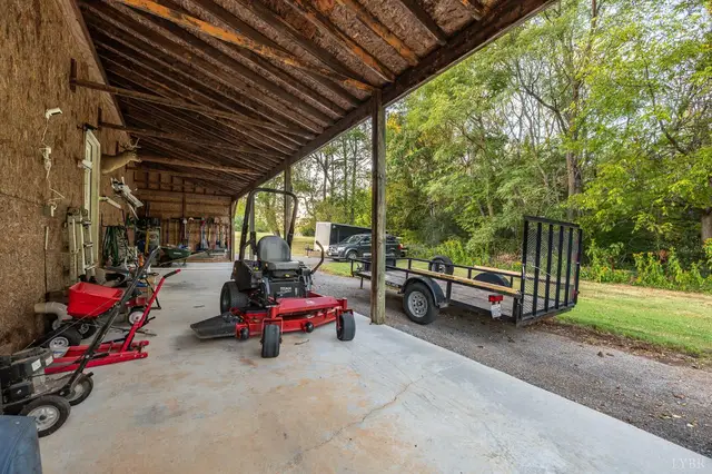 Covered lean-to with a riding mower and a utility trailer at 1351 Country Estates Drive, Lowry VA