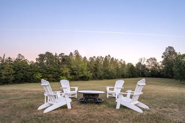 Backyard fire pit with white Adirondack chairs on the lawn at 1351 Country Estates Drive, Lowry VA