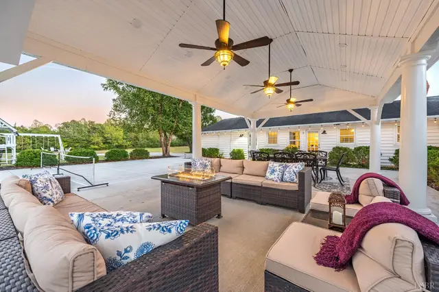Covered patio with wicker sectional seating and a fire table at 1351 Country Estates Drive, Lowry VA