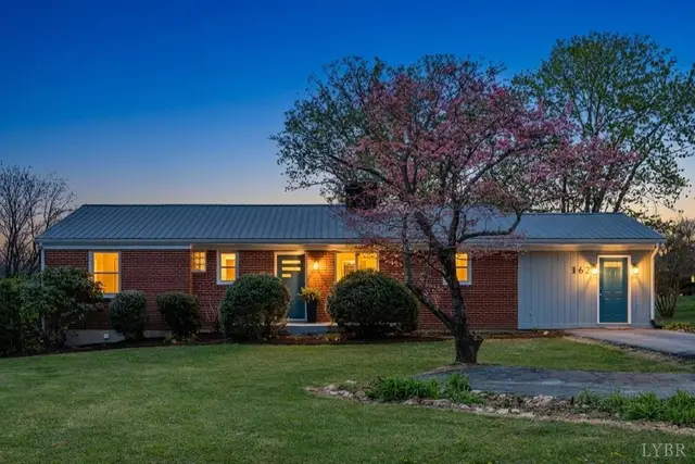 Front of the house, brick ranch with a metal roof and flowering tree at dusk at 162 Brooklawn Drive, Lynchburg VA