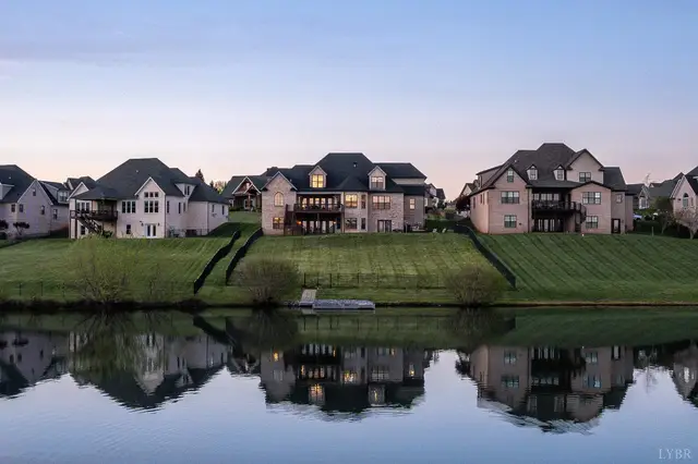 View across the lake of large homes reflected in the water at 1698 Lake Manor Drive, Forest VA