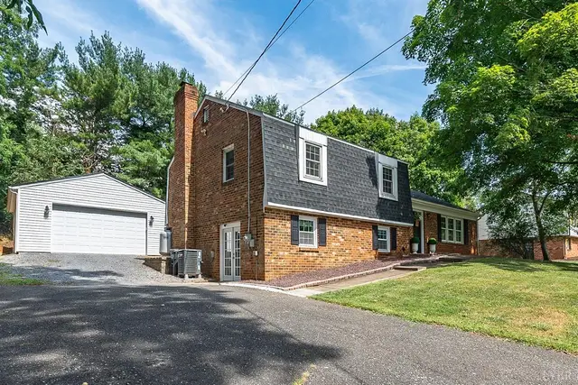 Side view of the brick house with a detached garage and paved driveway at 1706 Danbury Drive, Lynchburg VA