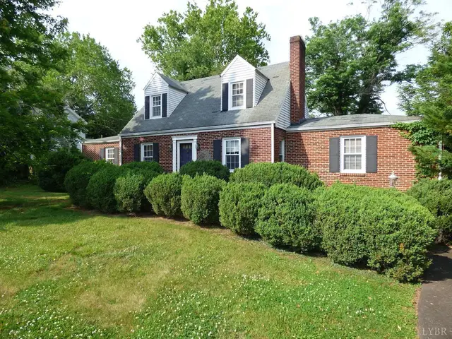 Front of the house, brick Cape Cod with dormers and rounded shrubs at 207 Garland Avenue, Amherst VA