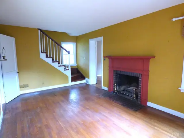 Living room with a red brick fireplace, hardwood floors and a staircase at 207 Garland Avenue, Amherst VA