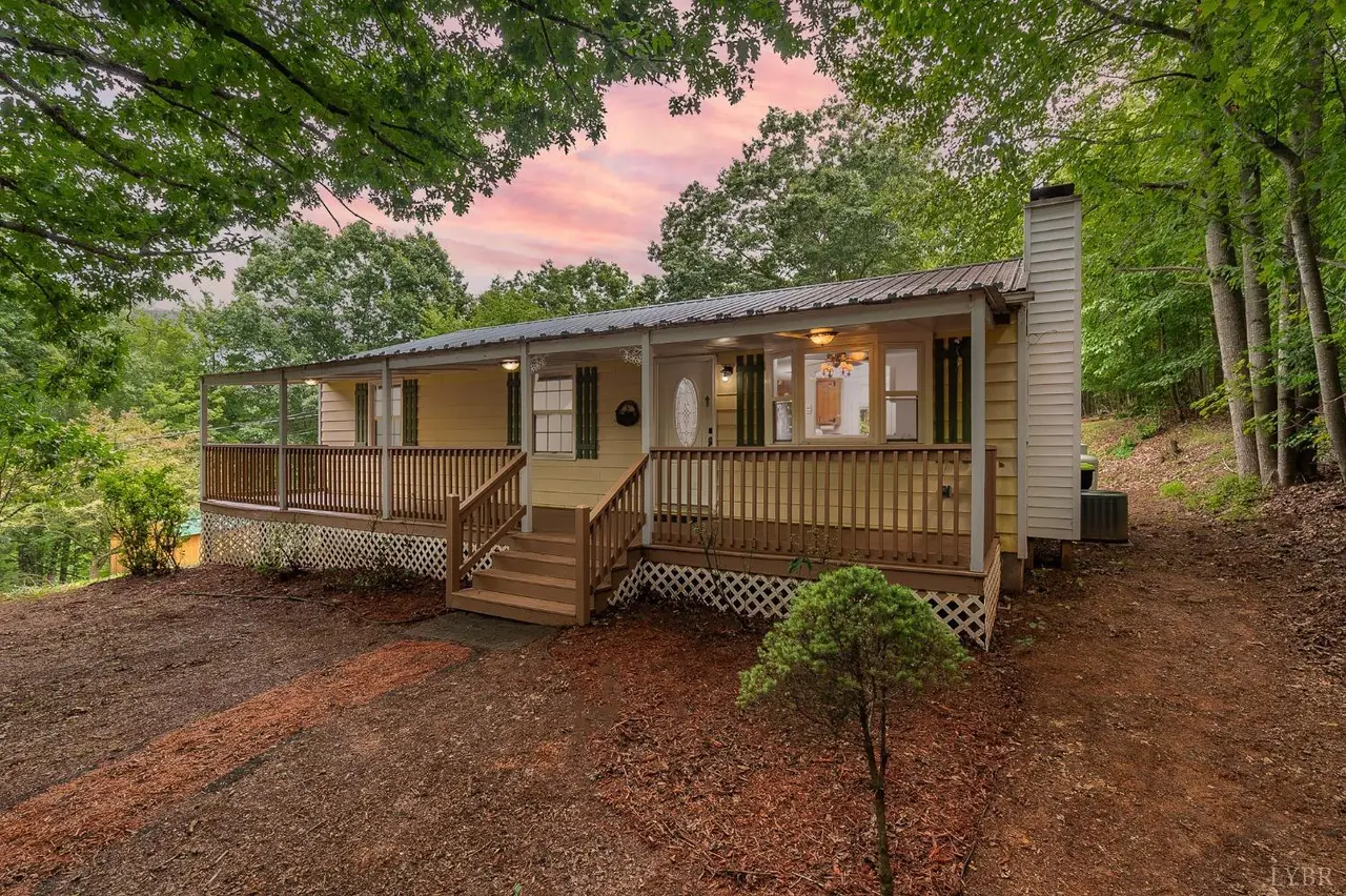 Front of the house with a wraparound wood porch and lattice skirting at dusk at 2087 Camp Hydaway Road, Lynchburg VA