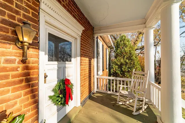 Front porch with white columns, a rocking chair and a wreathed door at 2601 Murger Street, Lynchburg VA