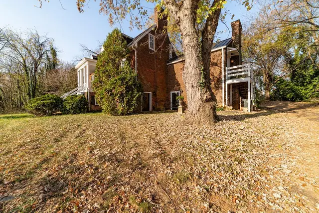 Side view of the brick house with chimneys and a large tree at 2601 Murger Street, Lynchburg VA
