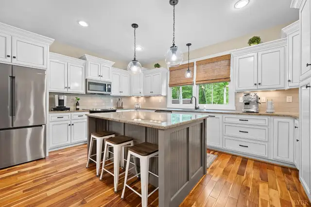 Kitchen with white cabinets and a gray island with bar stools at 2842 Chilton Road, Appomattox VA