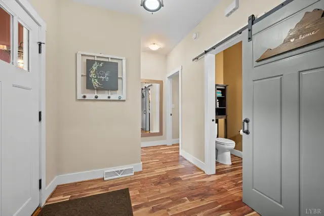 Hallway with a gray sliding barn door and a half bath at 2842 Chilton Road, Appomattox VA