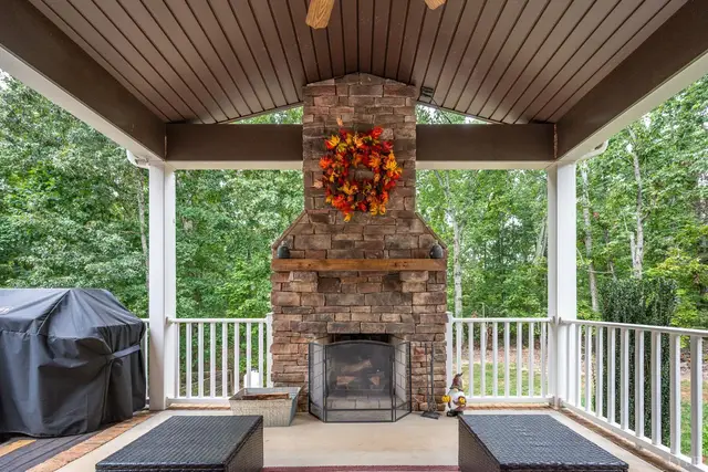 Covered porch with a stone fireplace and white railings at 2842 Chilton Road, Appomattox VA