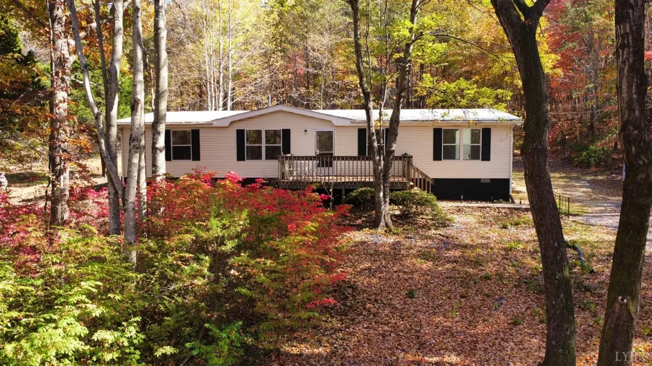 Front of the manufactured home with a wood deck among autumn trees at 312 Paradise Road, Concord VA