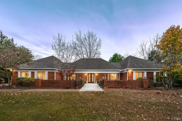 Front of the one-story brick house with lit windows at dusk at 405 Meadowridge Drive, Lynchburg VA