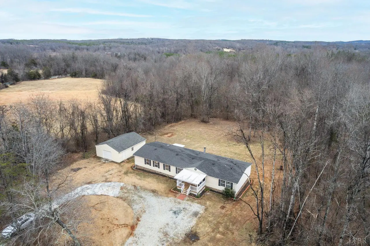 Aerial view of the manufactured home and outbuilding on a wooded lot at 568 Toytown Road, Amherst VA
