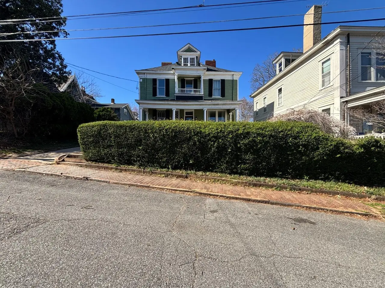 Street view of the two-story house behind a tall hedge at 611 Pearl Street, Lynchburg VA