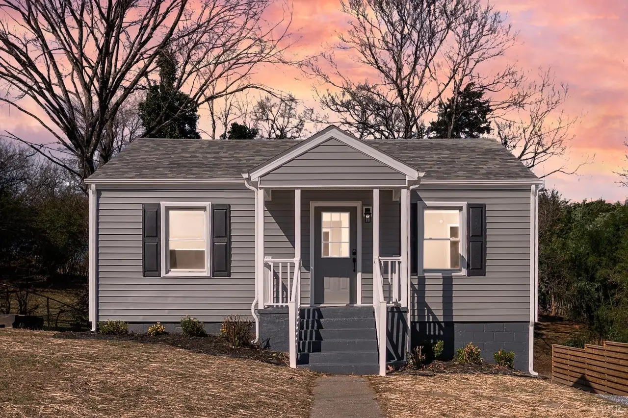 Front of the house with gray siding and a covered entry at sunset at 634 Thomas Road, Lynchburg VA