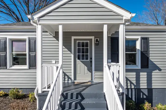 Covered front porch with white railings and a gray door at 634 Thomas Road, Lynchburg VA