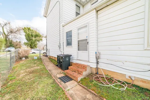 Side of the house with a back door, brick steps and chain link fence at 711 Norwood Street, Lynchburg VA