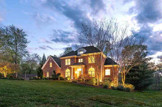 Angled front view of the brick house with lit windows at dusk at 1278 Jefferson Dr W, Forest VA