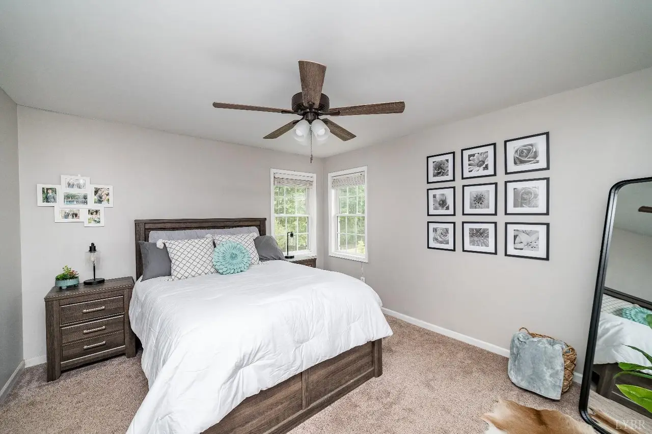 Bedroom with a white comforter, ceiling fan and framed photo wall at 94 Valleyview Drive, Madison Heights VA