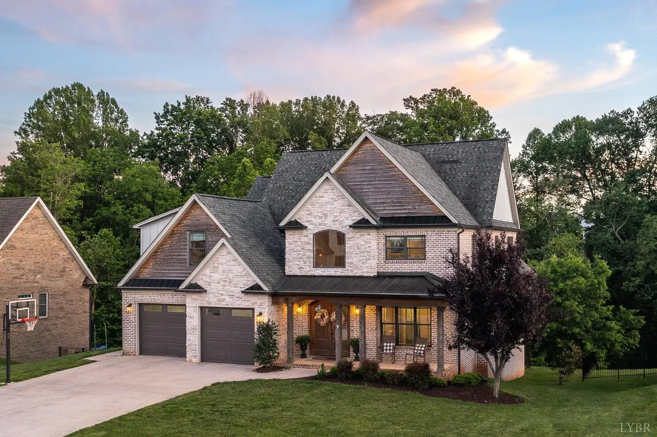 Front of the two-story brick house with a two-car garage at sunset at 951 Leander Drive, Forest VA