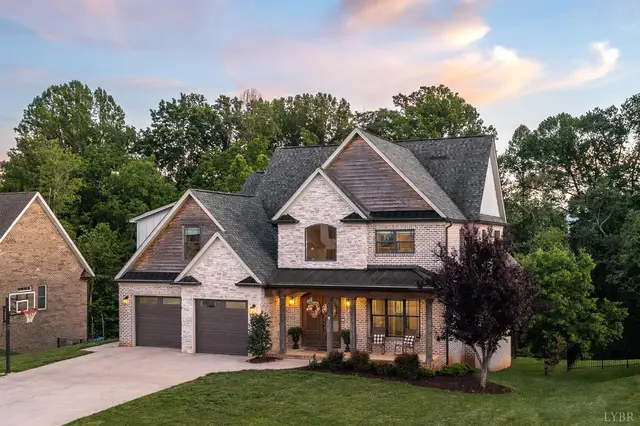 Front of the two-story brick house with a two-car garage at sunset at 951 Leander Drive, Forest VA